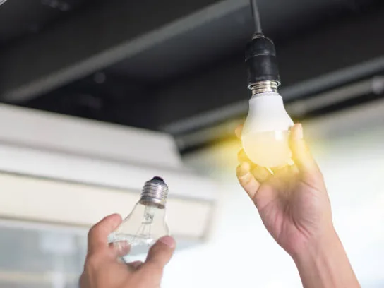 A hand changing a light bulb in a ceiling fixture