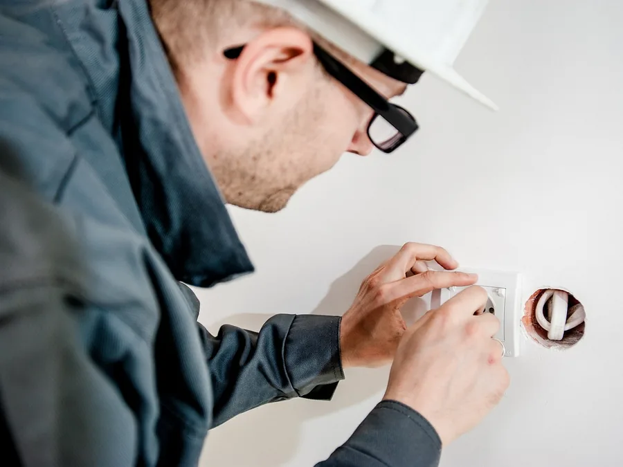 An electrician fitting a device into a wall box