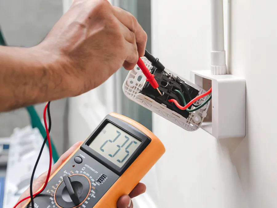 A multimeter testing a wall receptacle